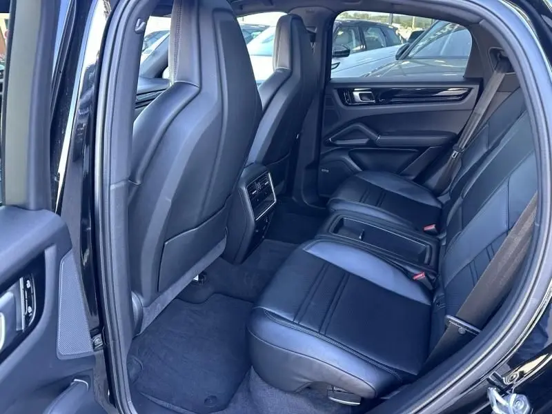 Vue intérieure arrière côté droit du Porsche Cayenne coupé 2020 noir métal, sièges cuir noirs et console centrale.