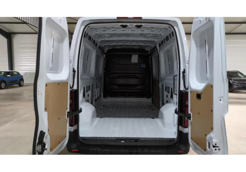 Vue arrière du Renault Master blanc 2025 avec portes ouvertes montrant l'espace de chargement vide et les panneaux intérieurs en bois.