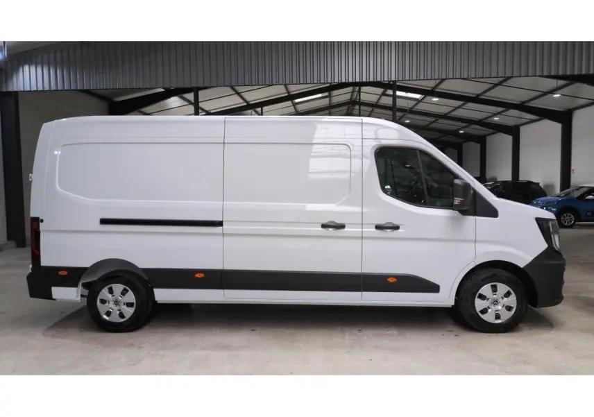 Profil côté droit du Renault Master blanc 2025 avec bandeau noir et roues argentées dans un garage.