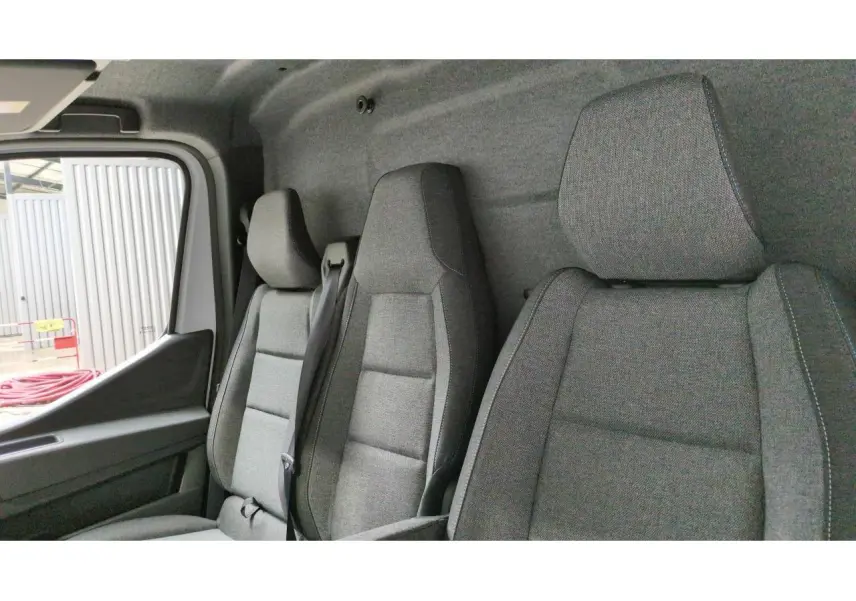Intérieur du Renault Master 2025 vu de côté gauche, montrant les sièges gris en tissu et la porte conducteur ouverte.