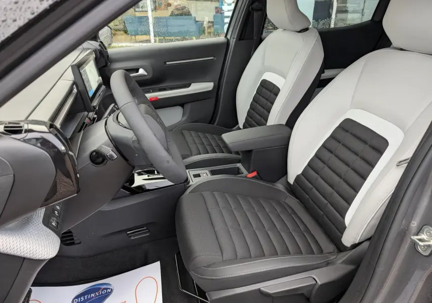 Intérieur avant droit du Citroën C3 Aircross 2025 avec sièges bicolores gris clair et noir, volant multifonctions et écran tactile.
