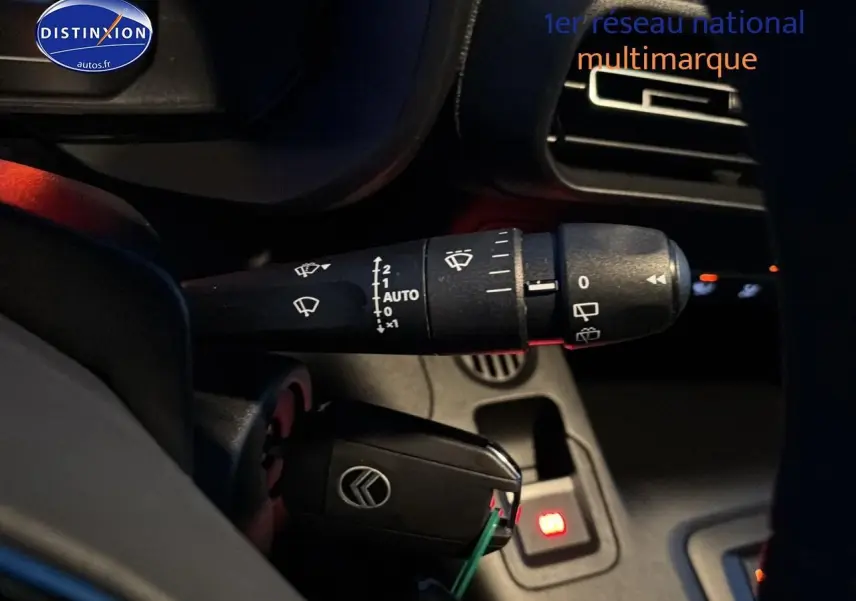 Gros plan sur la commande d'essuie-glace et la clé de contact du Citroën Berlingo Fourgon blanc, intérieur côté gauche.