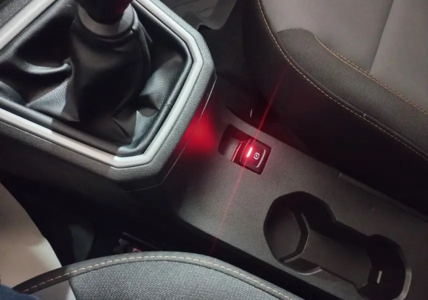Gros plan sur la console centrale de la Dacia Sandero 2024, avec levier de vitesse manuel et frein à main électrique allumé.