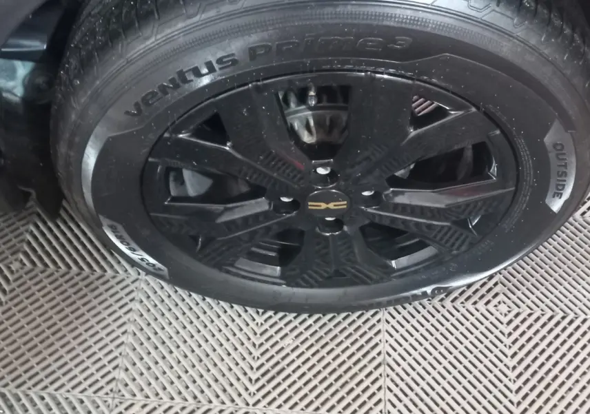 Gros plan sur la roue noire avec jante en alliage du côté gauche de la Dacia Sandero Extreme+ TCe 110 verte.