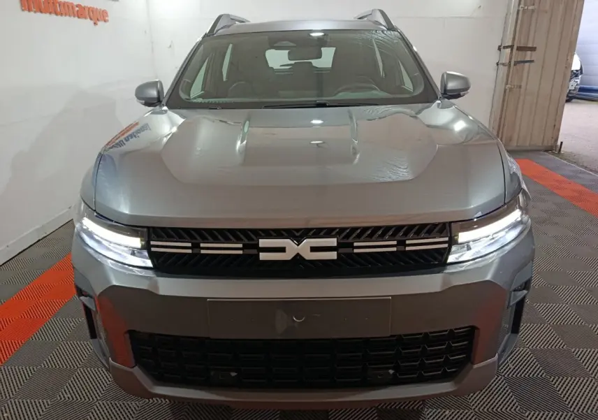 Vue frontale du SUV Dacia Bigster gris foncé avec phares LED allumés et calandre noire distinctive.