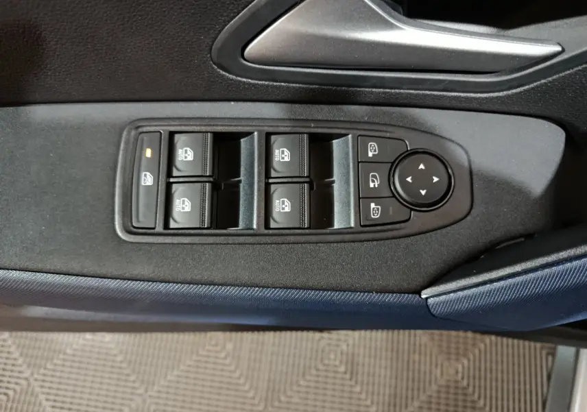 Vue rapprochée des commandes de lève-vitres et rétroviseurs sur la porte côté conducteur du Dacia Bigster gris foncé.