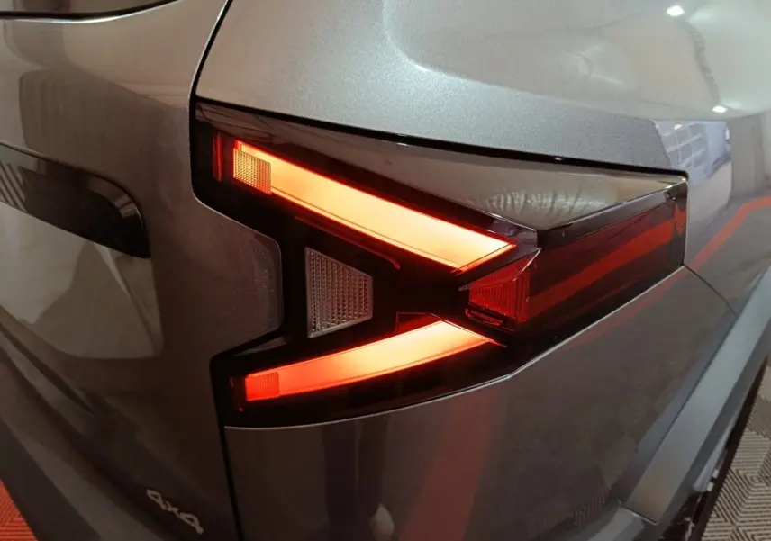 Gros plan sur le feu arrière droit rouge et orange du Dacia Bigster gris foncé 4x4, soulignant son design anguleux.