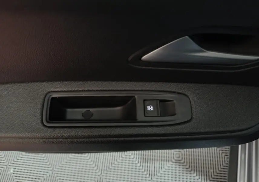 Détail de la commande de lève-vitre côté conducteur sur la porte intérieure d'une Dacia Bigster gris foncé.