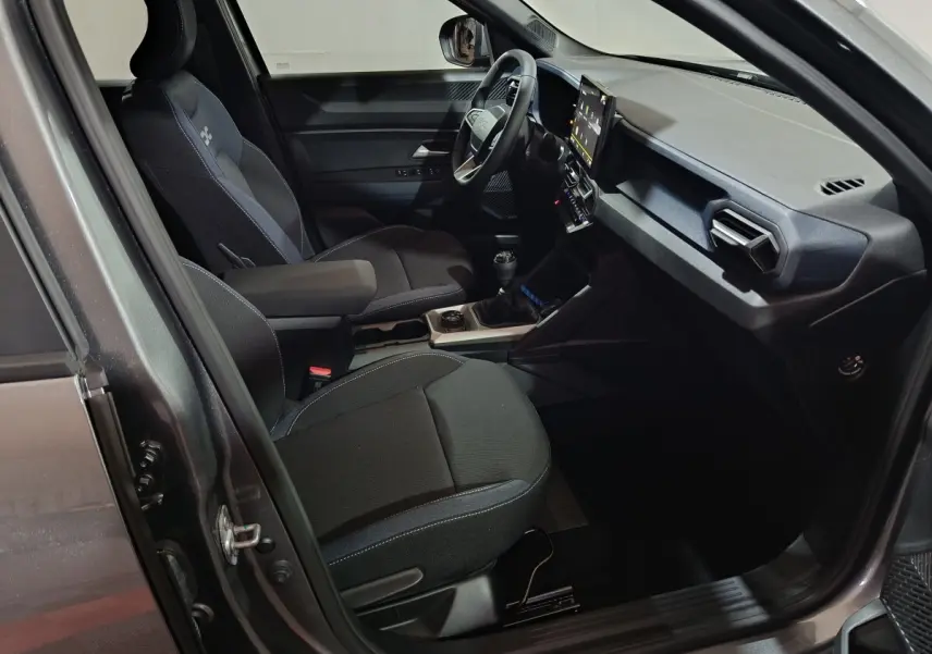 Vue intérieure côté conducteur du Dacia Bigster gris foncé, montrant les sièges, le volant et l'écran tactile central.
