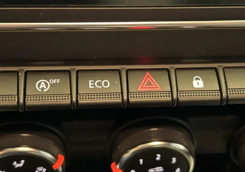 Gros plan sur les boutons de commande du tableau de bord de la Renault Clio V blanche, avec bouton ECO et alerte.