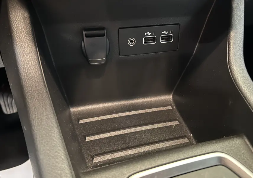 Gros plan sur la console centrale noire de la Renault Clio V 2025, montrant prises USB et prise jack.