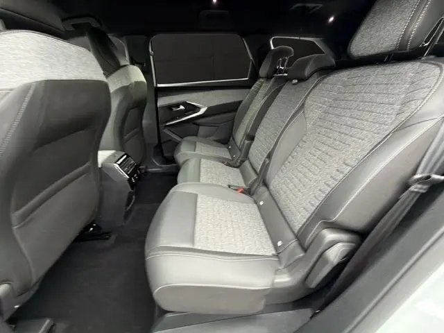 Vue latérale intérieure montrant la banquette arrière grise et noire du Peugeot 5008 blanc, version hybride 2025.