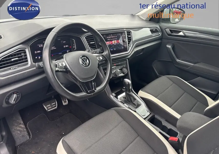 Vue intérieure côté conducteur du Volkswagen T-Roc 1.5 TSI 2021, avec tableau de bord numérique et sellerie noire à surpiqûres claires.