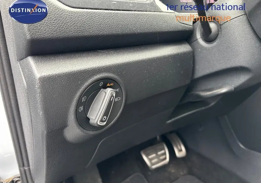 Gros plan sur le bouton de commande des phares à gauche du volant dans un Volkswagen T-Roc blanc argenté.