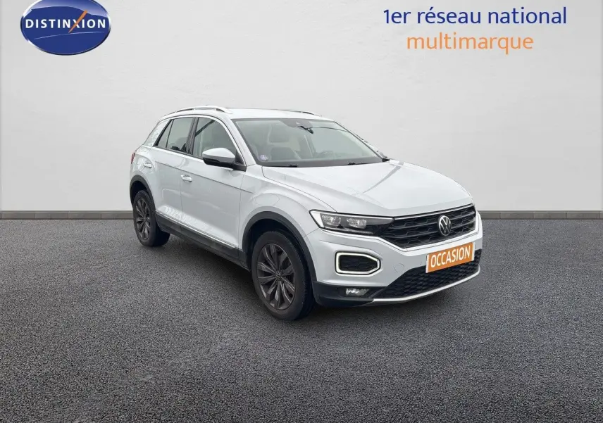 Volkswagen T-Roc blanc argenté en 3/4 avant droit avec jantes foncées sur sol gris.