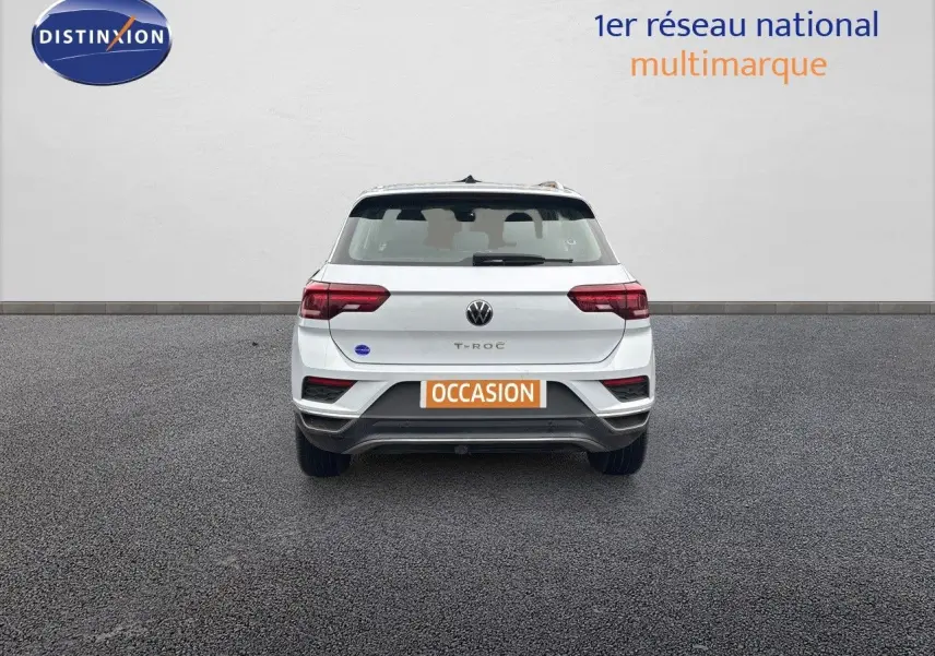 Vue arrière d'un Volkswagen T-Roc blanc argenté 2021 avec plaque orange "OCCASION" sur un sol gris.