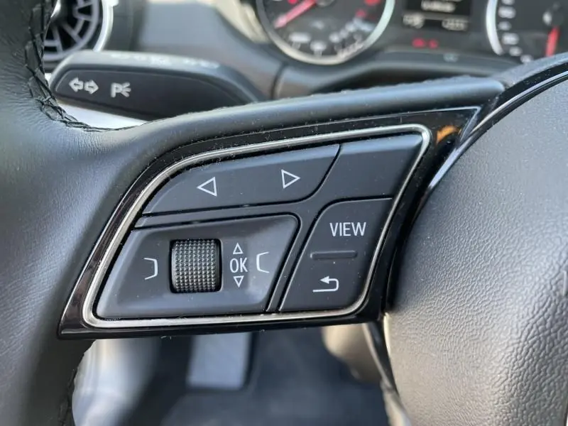 Gros plan sur les commandes multifonctions noires à gauche du volant de l'Audi Q2 noir métal 2022.