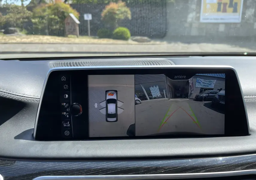 Écran central de la BMW Série 7 noire montrant la caméra de recul et l'affichage 360° du stationnement.