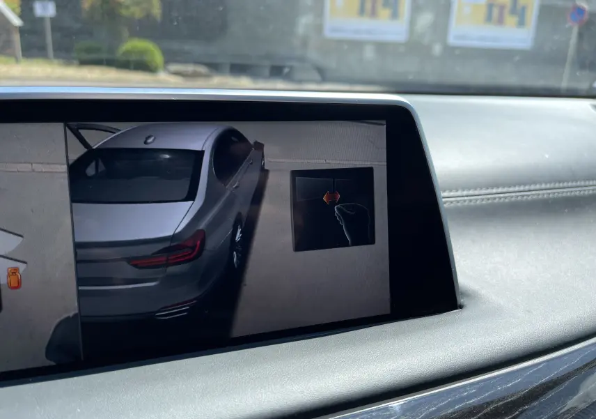 Vue écran intérieur montrant la BMW Série 7 noire en 3/4 arrière droit sur l'affichage de stationnement assisté.