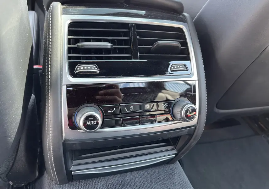 Vue rapprochée de la console de climatisation arrière noire avec commandes rotatives dans une BMW Série 7 G11 M Sport 2015.
