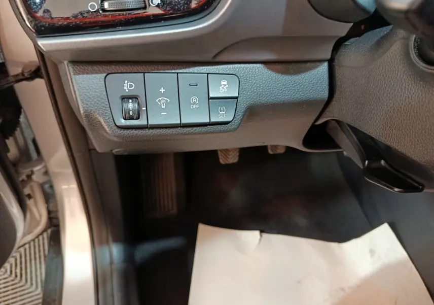 Vue intérieure côté gauche du tableau de bord gris du Kia Stonic 2022, avec commandes d’éclairage et aides à la conduite.