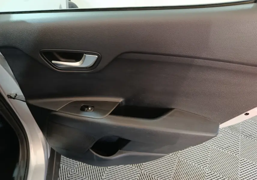 Vue intérieure du panneau de porte avant gauche gris clair du KIA STONIC 2022 avec poignée argentée et commande de vitre.