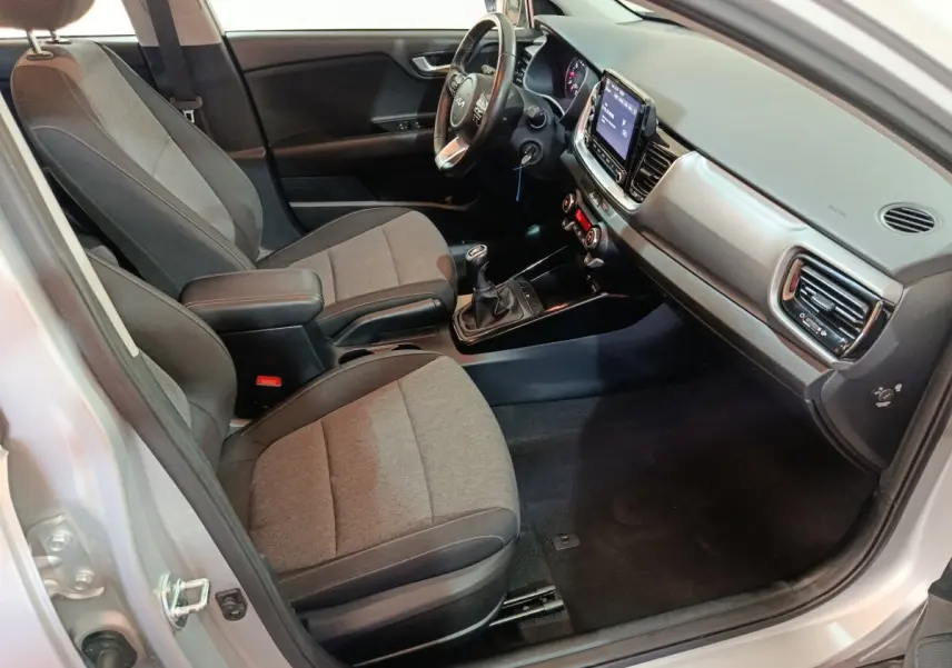 Vue intérieure côté conducteur du Kia Stonic gris clair 2022, avec tableau de bord moderne et boîte manuelle visible.