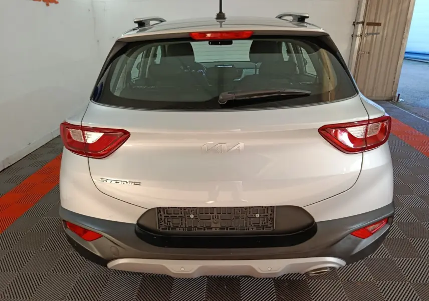 Vue arrière d'un KIA Stonic gris clair 2022 avec feux arrière allumés et pare-chocs noir contrastant.