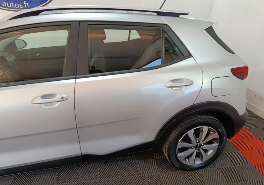 Vue latérale droite d'un KIA Stonic gris clair 2022, mettant en valeur les jantes alliage et les contours noirs des passages de roues.