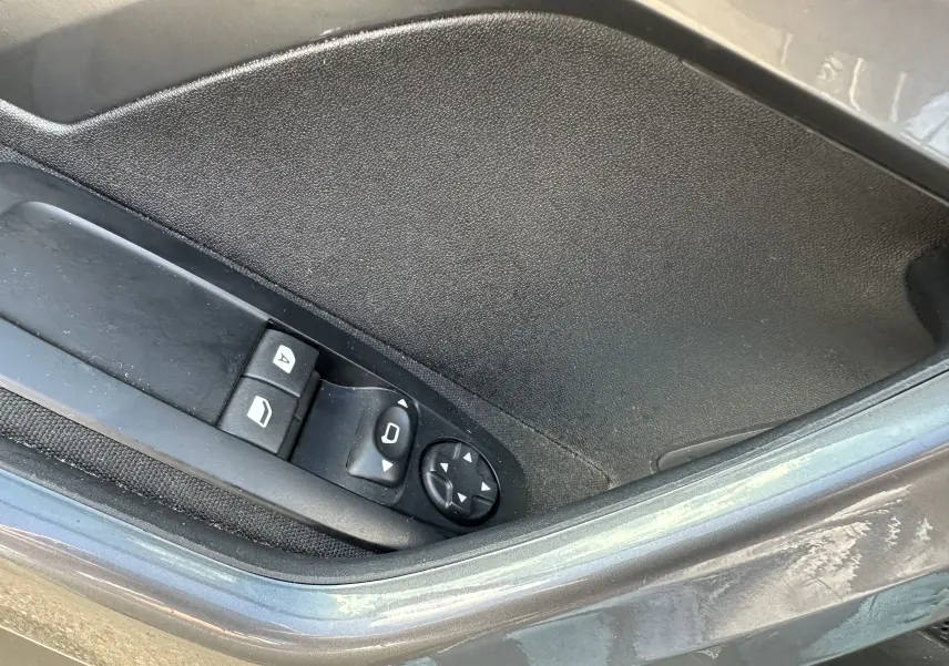 Détail des commandes électriques des vitres et rétroviseurs sur la porte côté gauche d’un Peugeot 2008 gris 2019.