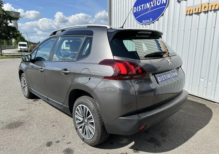 Vue 3/4 arrière côté gauche d'un Peugeot 2008 gris 2019 avec jantes alliage et feux arrière distinctifs.