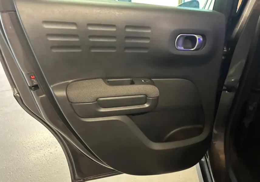 Vue rapprochée de la porte arrière gauche du Citroën C3 Aircross gris platinium métal avec accoudoir en tissu gris noir.