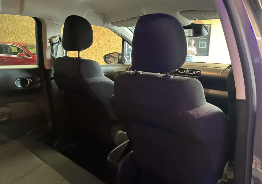 Intérieur arrière du Citroën C3 Aircross 2023, sièges tissu gris noir, vue depuis la porte arrière droite ouverte.