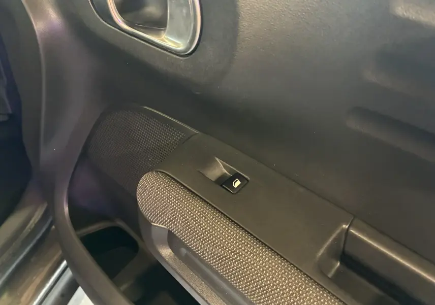 Gros plan sur la commande de lève-vitre côté conducteur avec tissu gris noir et poignée intégrée sur porte Citroën C3 Aircross.