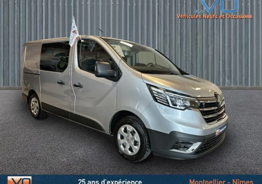Renault Trafic Fourgon gris en 3/4 avant droit, avec vitres surteintées et calandre noire brillante.