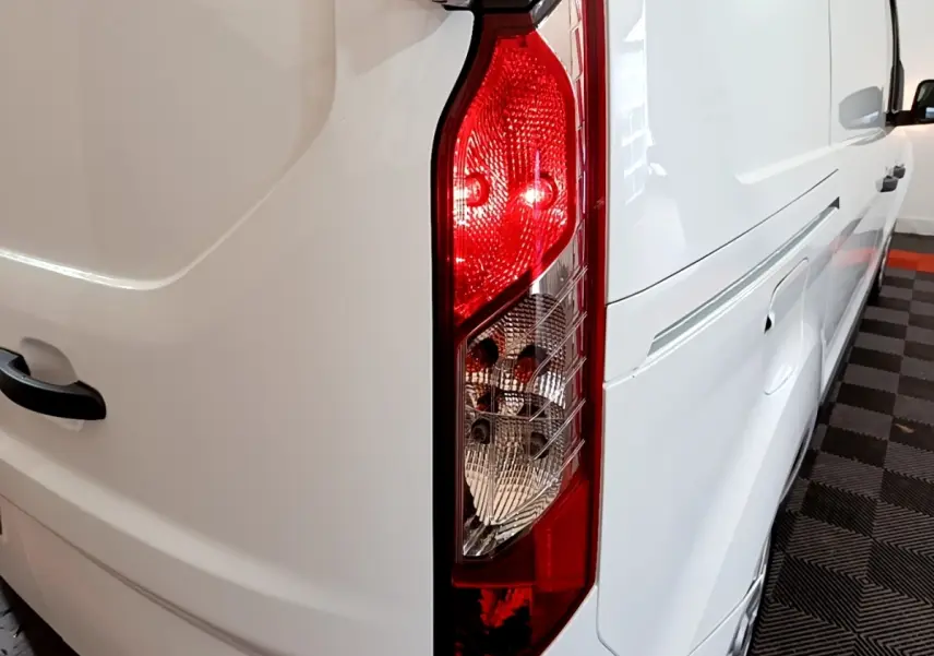 Gros plan sur le feu arrière droit d’un Ford Transit Fourgon blanc, avec vue partielle du flanc droit et de la porte arrière.