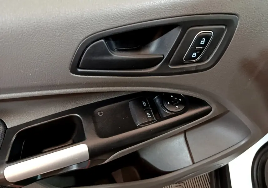 Gros plan sur la poignée intérieure et les commandes de vitres côté conducteur du Ford Transit Fourgon blanc, version 2022.