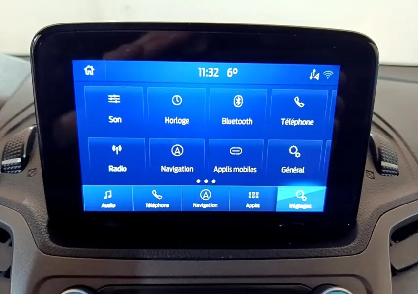 Écran tactile central bleu affichant les options multimédia du Ford Transit Fourgon blanc, vue intérieure frontale.