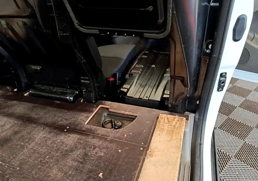 Vue intérieure côté droit du fourgon blanc Ford Transit, montrant l'espace de chargement et une cloison partielle.