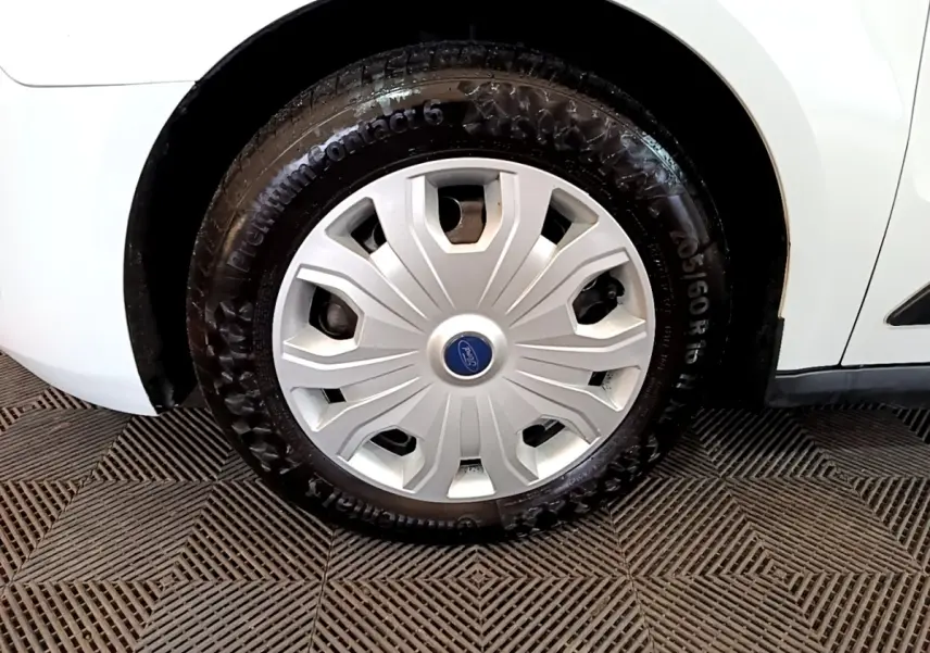 Gros plan sur la roue avant droite blanche du Ford Transit Fourgon 2022 avec enjoliveur argenté et logo Ford bleu.