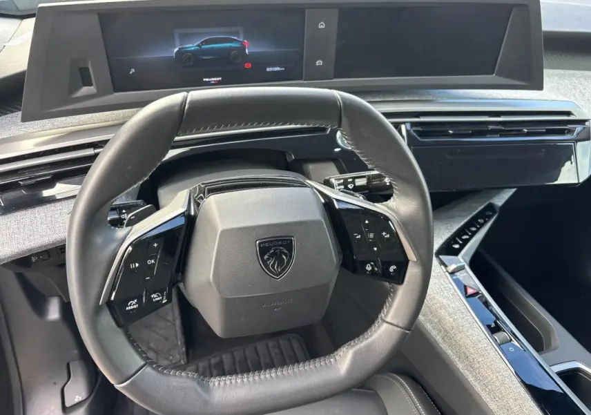 Vue intérieure centrée sur le volant cuir et le cockpit numérique du Peugeot 3008 Hybrid gris 2025.