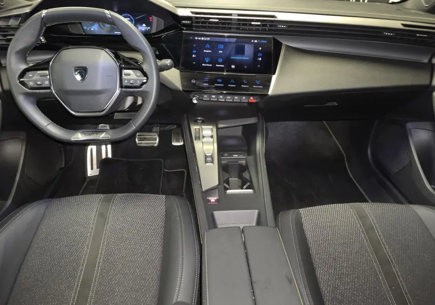 Vue intérieure avant de la Peugeot 408 GT 2025, tableau de bord noir avec écran tactile 10 pouces et volant cuir perforé.