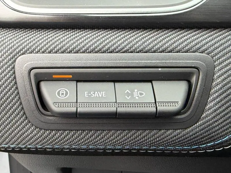 Gros plan sur les boutons de commande du tableau de bord du Renault Captur 1.8 E-Tech hybride 2026, finition Esprit Alpine.