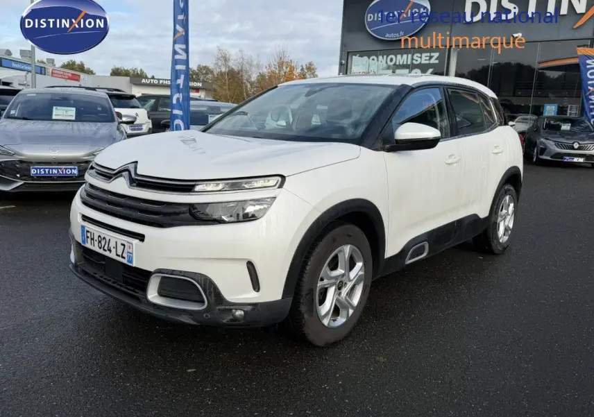 Vue 3/4 avant d'un Citroën C5 Aircross blanc nacré avec détails noirs et jantes argentées sur fond neutre.