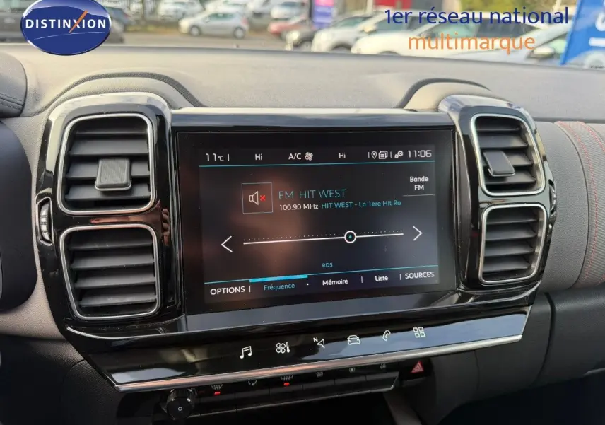 Écran tactile central allumé avec radio FM, entouré de deux aérateurs noirs sur tableau de bord gris du Citroën C5 Aircross.