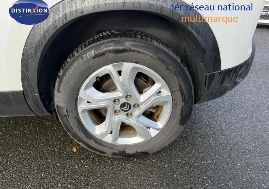 Gros plan sur la roue avant droite d'un Citroën C5 Aircross blanc nacré avec jante alliage cinq branches.