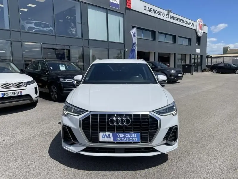 Audi Q3 blanc vue de face, mettant en valeur la calandre S-Line distinctive et les phares LED modernes.
