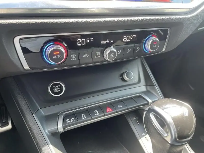Détail du tableau de bord de l'Audi Q3 blanc 2021 montrant la climatisation digitale et la commande Start/Stop.