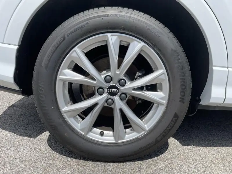 Gros plan sur la roue avant droite d'un Audi Q3 blanc 2021 avec jante alliage S-Line et pneu Hankook.