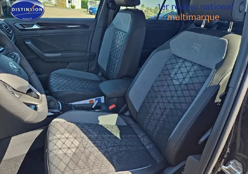 Vue intérieure côté gauche du Volkswagen T-Roc 2025 noir perle, sièges tissu R-Line avec surpiqûres et volant cuir sport.